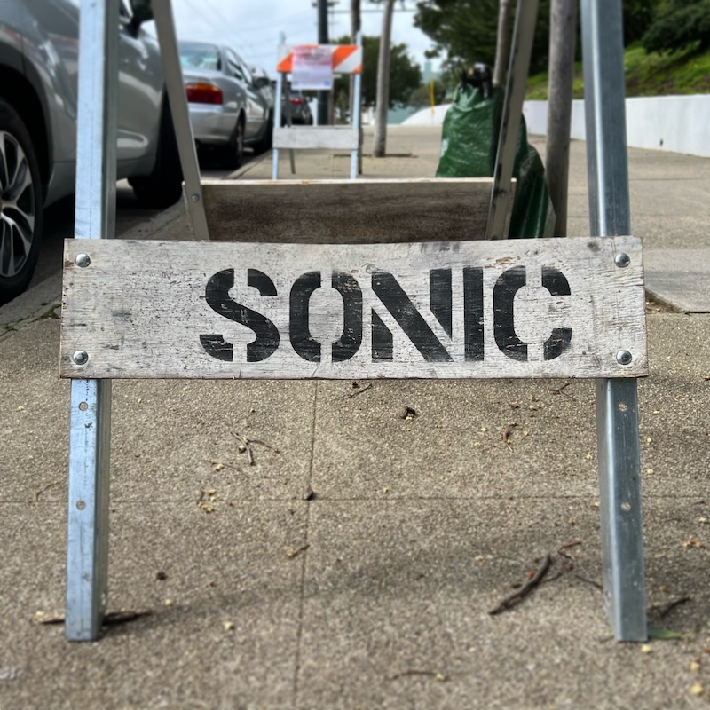 It's a sandwich-board sign on the sidewalk that simply reads "SONIC" in stenciled letters